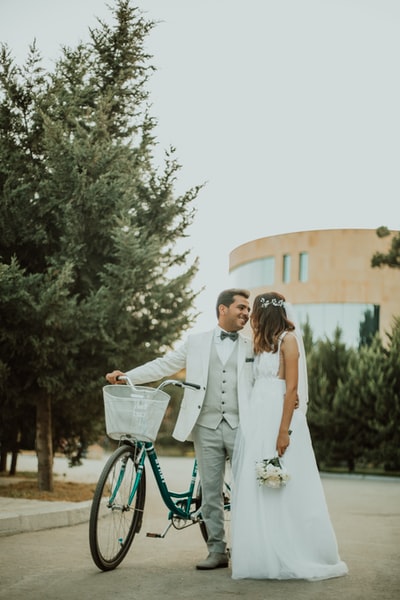 男人和女人穿着婚纱在自行车旁边附近树白天
